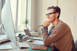 © Seventyfour - Side view portrait of adult businessman looking at computer screen and smiling while working at desk in modern office, copy space
