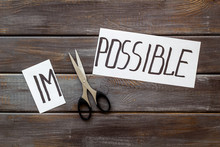 All Is Possible Concept. Cut Word Impossible Near Scissors On Dark Wooden Background
