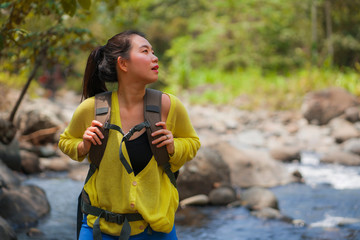 young beautiful and happy Asian Japanese woman carrying backpack trekking on mountains crossing river enjoying holiday nature and fresh environment hiking cheerful