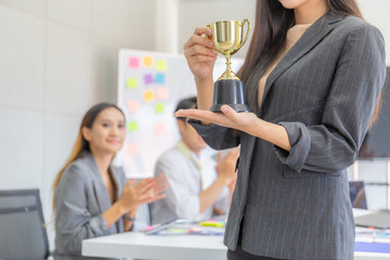 business woman holding award trophy at meeting room, celebration success happiness team concept