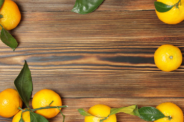 Tangerines with leaves on a wooden background. Copy space.