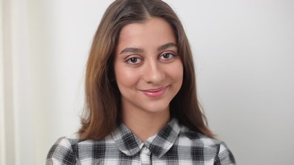 Wall Mural - Portrait of a young Indian female student on a white background. Beautiful smiling brunette girl.