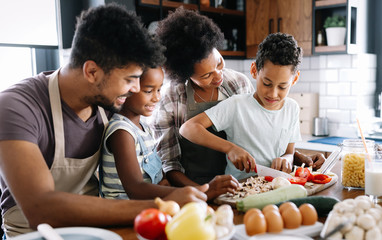 Wall Mural - happy family in the kitchen having fun and cooking together. healthy food at home.