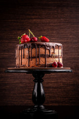 Chocolate cake with with berries, strawberries and cherries. cake on a dark brown background. copy space