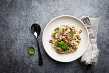Risotto With Mushrooms In A White Plate Over Gray Background, Top View