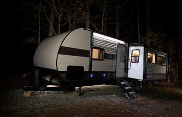 Towed camping trailer at Jordan Lake State Park in North Carolina at night with lights on inside.