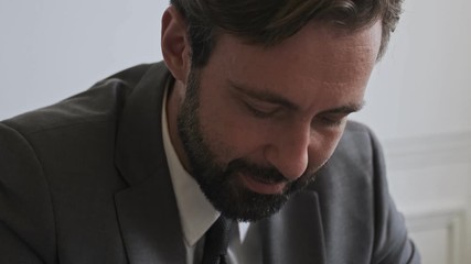 Sticker - Close up view of Smiling concentrated handsome bearded businessman working at office