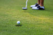 Close up golf ball woman putting golf ball in hole tee with club in golf course on evening on time for healthy sport.   Lifestyle and Sport Concept