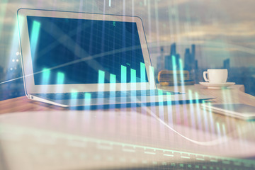 Stock market graph on background with desk and personal computer. Double exposure. Concept of financial analysis.