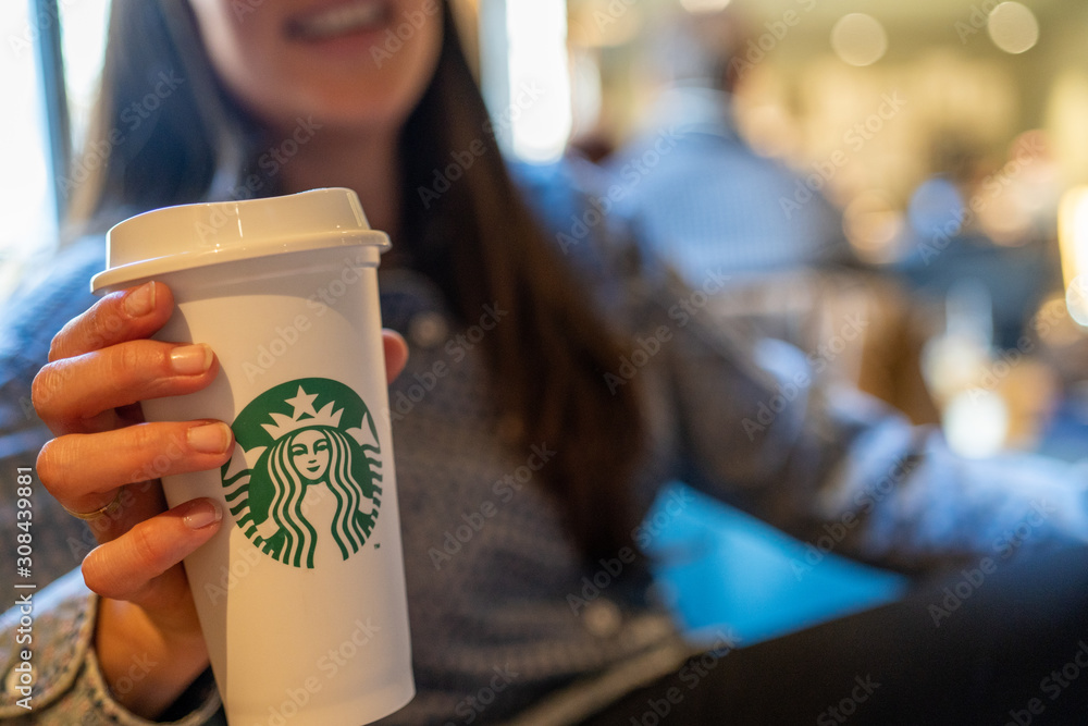 New York, USA - December 1, 2019 : Happy Caucasian Girl Holding a Tall Cup  of Starbucks Coffee in Starbucks Coffee Store. Stock Photo | Adobe Stock