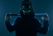 Anonymous criminal man with baseball bat in a black hoodie and neon mask