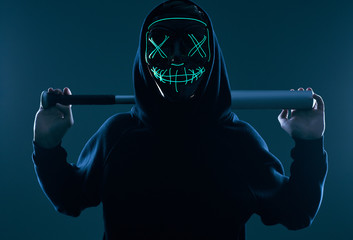 Wall Mural - Anonymous criminal man with baseball bat in a black hoodie and neon mask