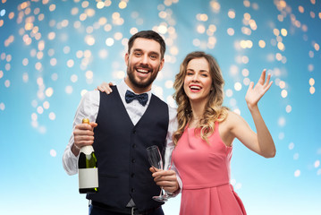 Wall Mural - celebration and people concept - happy couple with bottle of champagne and glasses over holiday lights on blue background