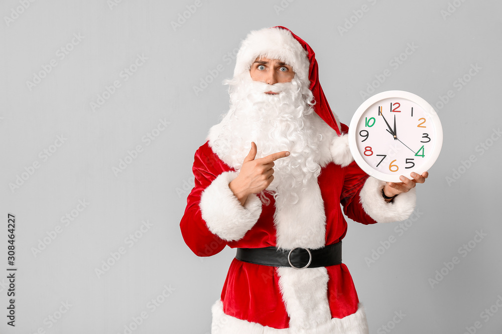 Santa Claus with clock on light background. Christmas countdown concept