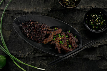 Sticker - Traditional Chinese spicy meal made of beef meat, black rice and black pepper sauce on a dark wooden table. Directly above top view shot.