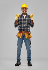 profession, construction and building - happy smiling indian worker or builder in helmet and gloves with tool belt over grey background