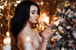 Christmas. Beautiful smiling woman. Happy New Year. Sexy model girl with glass of champagne at party, drinking champagne over holiday glowing background. Joy happiness. Miracles.
