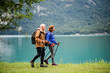 © Halfpoint - A side view of senior pensioner couple hiking by lake in nature.