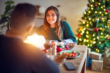 Wall Mural - Young beautiful couple smiling happy and confident. Eating food celebrating christmas at home