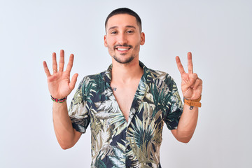 Wall Mural - Young handsome man wearing Hawaiian summer shirt over isolated background showing and pointing up with fingers number seven while smiling confident and happy.