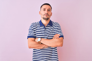 Sticker - Young handsome man wearing nautical striped t-shirt over pink isolated background skeptic and nervous, disapproving expression on face with crossed arms. Negative person.