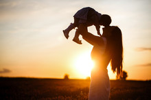 A Mother Lifts A Toddler Child In The Air Above A Picturesque Sunset Sky. A Woman And A Little Girl In A Field Of Lavender Flowers. Copy Space