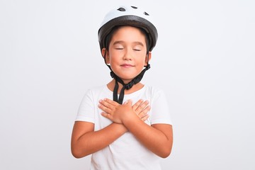 Sticker - Beautiful kid boy wearing bike security helmet standing over isolated white background smiling with hands on chest with closed eyes and grateful gesture on face. Health concept.