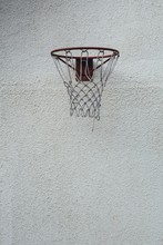 Vertical Picture Of A Red Basketball Hoop On A Dirty White Wall During Daytime