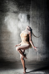 incredibly beautiful pose of a dancer with flying flour on a gray background.beautiful girl ballerin