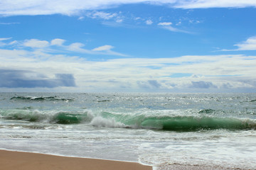 Atlantic ocean, green water, waves, ocean foam, wet sand, white clouds, blue bright saturated sky, Portugal