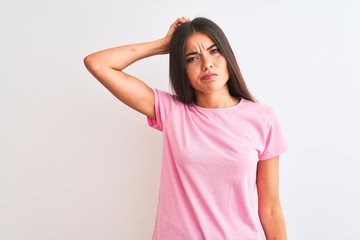 Wall Mural - Young beautiful woman wearing pink casual t-shirt standing over isolated white background confuse and wonder about question. Uncertain with doubt, thinking with hand on head. Pensive concept.
