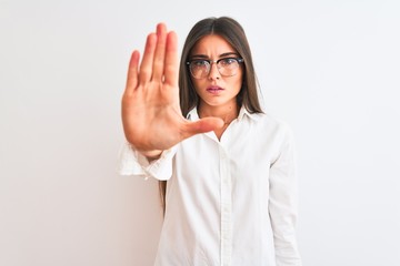 Poster - Young beautiful businesswoman wearing glasses standing over isolated white background doing stop sing with palm of the hand. Warning expression with negative and serious gesture on the face.
