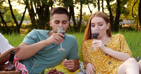 Canvas Print - Happy young couple with wine having picnic in park