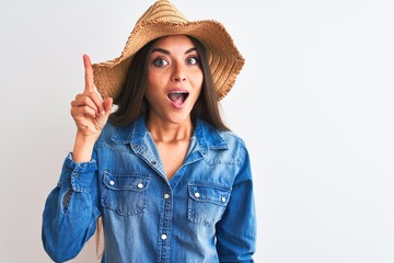 Poster - Young beautiful woman wearing denim shirt and hat standing over isolated white background pointing finger up with successful idea. Exited and happy. Number one.