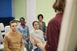 © AnnaStills - Group of young people sitting on chairs and listening to their teacher attentively