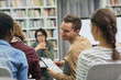 © AnnaStills - Young man with report talking to his colleagues during business presentation in the library