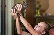 © Cavan Images - Teen girl smiles as she lifts tiny black kitten high in the air