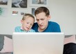 © Cavan Images - father and soon smiling looking at a laptop at home together