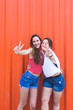 © Cavan Images - Two happy cheerful teenage girls in showing peace gesture