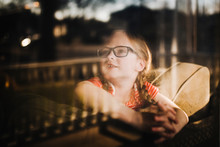 Front View Of Little Girl Looking Out Of Window With Reflections