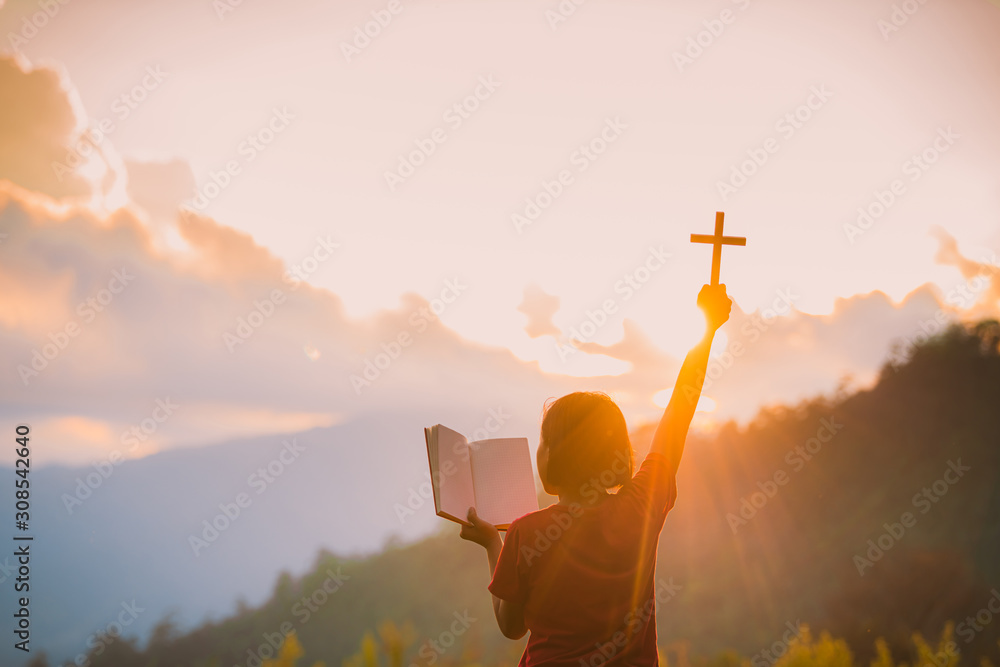 The silhouette of a woman's hand, praying spiritually over the sun ...