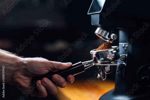 Fotografía ground coffee pouring into a portafilter with a grinder