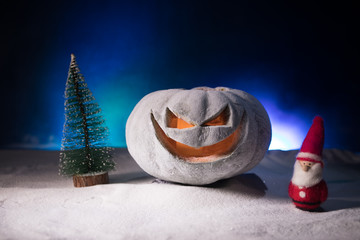 Christmas New Year or Halloween Celebrate Background with Little Christmas Tree on Blurred Bokeh Snow Background with horror pumpkin