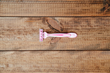 Canvas Print - A female razor on a wooden table. The concept of doing makeup, caring for the appearance of women. Shaving hair on the woman's body.