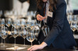 © Federico Magonio - Waitress set the tables with crystal gobles for a wine tasting workshop. Catering service and dining room staff at work.