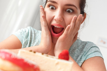 Canvas Print - Junk Food. Chubby girl sitting at kitchen looking at cake shouting excited close-up