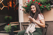 © zadorozhna - Beautiful woman using phone sitting in street cafe.