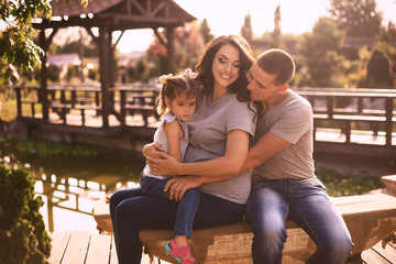 Happy pregnant family with little girl having fun in summer nature