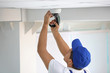 © New Africa - Technician installing CCTV camera on ceiling indoors