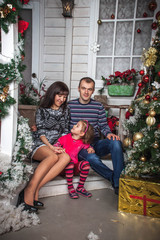 Wall Mural - family dad mom and daughter sitting on the steps of the house with Christmas decor